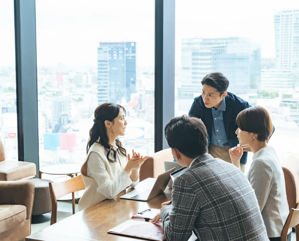 会議室で打ち合わせをする4人のビジネスパーソン
